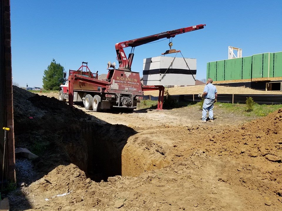 Lowering a concrete septic tank into the excavated hole